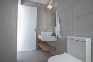 a bathroom with a white toilet and a sink at Kube Luxury Villas in Ayia Napa