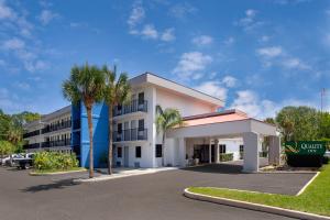 a hotel with palm trees in front of a parking lot at Quality Inn Atlantic Beach-Mayo Clinic Jax Area in Atlantic Beach