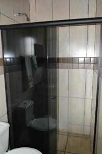 a bathroom with a toilet and a glass shower door at Hotel Poloni in Itapetininga