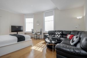 a bedroom with a bed and a black leather couch at Oxford Street Homestay in London