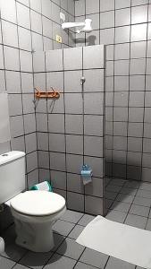 a bathroom with a toilet in a tiled wall at Pousada Tô Em Casa! in João Pessoa