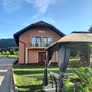 a house with an umbrella and chairs in front of it at Rooms Marijanović Plitvice in Vrelo Koreničko