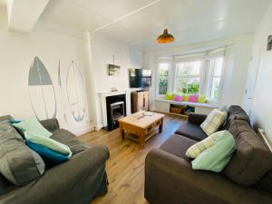 a living room with two couches and a table at Driftwood Cottage in Bude