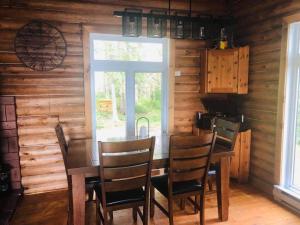 uma sala de jantar com uma mesa e cadeiras e uma janela em Le chalet au souvenir em Bouchette