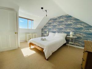 a bedroom with a large bed with a blue and white wall at Driftwood Cottage in Bude
