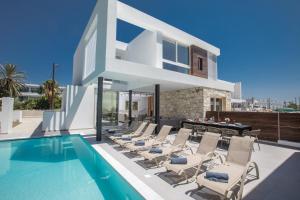 a villa with a swimming pool and lounge chairs at Kube Luxury Villas in Ayia Napa