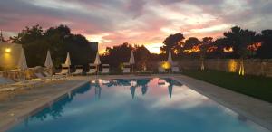 a pool with chairs and a sunset in the background at Il casale Falagario Stacca in Altamura