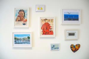 a wall of framed pictures on a white wall at Bright Chelsea Garden Nest in London