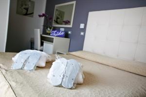 twee witte handdoeken bovenop een bed bij Hotel Iride & Spa in Cesenatico