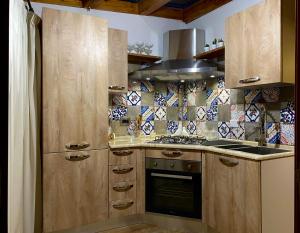 a kitchen with wooden cabinets and a stove top oven at Sole apartment in Taormina