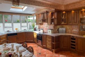 a large kitchen with wooden cabinets and a table with chairs at Glenmount Castleblayney in Castleblayney