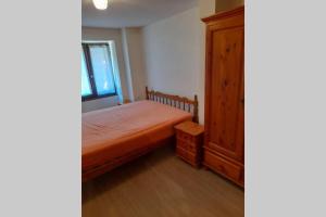a bedroom with a bed and a wooden cabinet at Charmant petit appartement avec bel exterieur. in Saint-Amarin