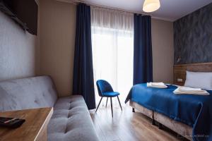 a bedroom with a bed and a couch and a window at Origami Prestige in Koszalin +28 photos