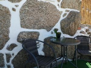 a table and two chairs next to a stone wall at Refúgio d’Aldeia da Serra in Seia
