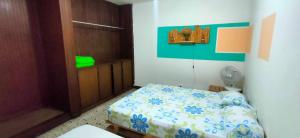 Dormitorio pequeño con cama con manta azul y blanca en Hostal Rich, en Medellín