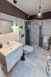a bathroom with a sink and a shower and a toilet at Apartamenty Świętokrzyska in Leszno
