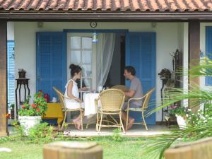 a couple sitting at a table on the porch of a house at Aretê Ilha Grande in Abraão