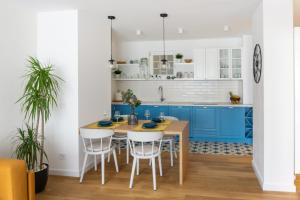 una cocina con armarios azules y una mesa y sillas de madera. en Akiton Apartment en Belgrado