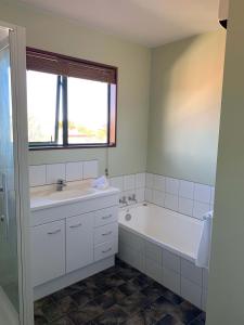 a white bathroom with a tub and a sink at 3 Bedroom Apartment, Kaikoura in Kaikoura
