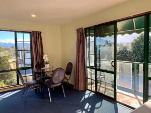 a room with a table and chairs and large windows at 3 Bedroom Apartment, Kaikoura in Kaikoura