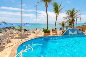 una piscina con el océano al fondo en Happy 313 apartamento Frente mar, en Natal