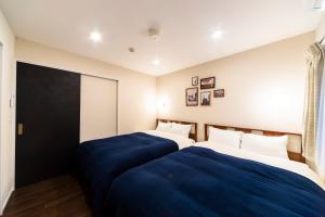 two beds in a hotel room with blue sheets at GIVE Shibuya Hon-Machi in Tokyo