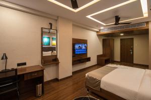 1 dormitorio con 1 cama y TV en Windstone Residency en Coimbatore