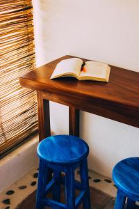 een open boek op een houten tafel met twee blauwe krukken bij Hotel el Risco in Cuatunalco