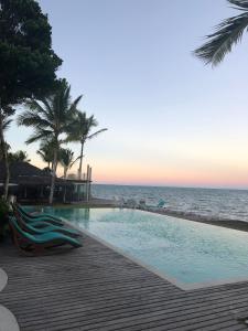una piscina junto al océano con palmeras en Arraial Praia Hotel Pousada, en Arraial d'Ajuda