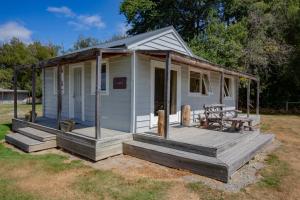 Casa pequeña blanca con porche de madera en The Cabin, Omahau Downs, en Twizel