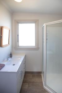 a white bathroom with a shower and a sink at The Cabin, Omahau Downs in Twizel