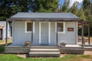 una pequeña casa blanca con porche y puerta en The Cabin, Omahau Downs, en Twizel