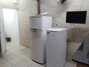 Dois frigoríficos brancos num quarto com uma televisão em casa com piscina aquecida e churrasqueira em Praia Grande na Praia Grande