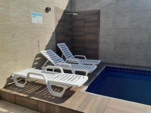Duas espreguiçadeiras e uma piscina num edifício em casa com piscina aquecida e churrasqueira em Praia Grande na Praia Grande