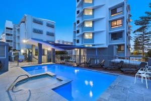 
a hotel room with a pool table and chairs at Cerulean Apartments in Caloundra
