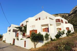 un edificio blanco con una montaña en el fondo en Froudi Rooms, en Kamarai