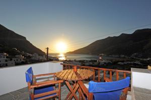 a table and chairs on a balcony with the sunset at Froudi Rooms in Kamares