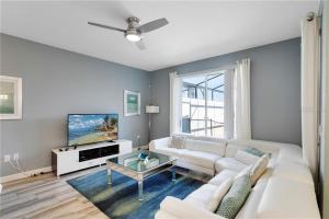 ein Wohnzimmer mit einem weißen Sofa und einem TV in der Unterkunft Storey Lake 4 Bedroom Townhome townhouse in Kissimmee