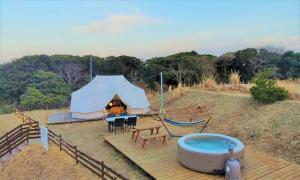 a tent with a table and chairs and a hot tub at Kabuku Resort in Shima