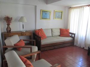 a living room with a couch and orange pillows at Aguada Chica Bungalows in Villa Carlos Paz