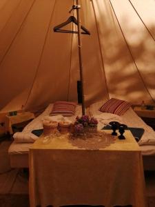 a bed in a tent with a table with flowers on it at Naturglamping in Kristianstad