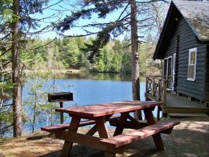 una mesa de picnic frente a una cabaña junto a un lago en Robinson's Cottages en Township of Edmunds