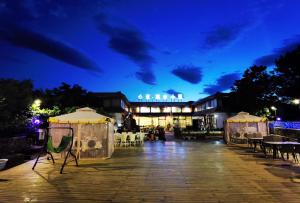 Xindao Xitai Xiaozhu Hotel في Huangkan: فناء في الليل مع طاولات وخيام