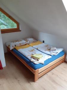 Schlafzimmer mit einem Bett mit blauer Bettwäsche und einem Fenster in der Unterkunft Kyprův mlýn in Knínice