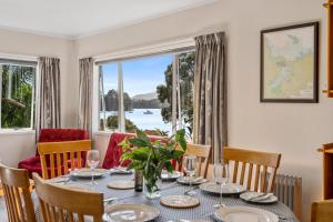 ein Esszimmer mit einem Tisch, Stühlen und einem Fenster in der Unterkunft Ota Point Paradise - Whangaroa Holiday Home in Whangaroa
