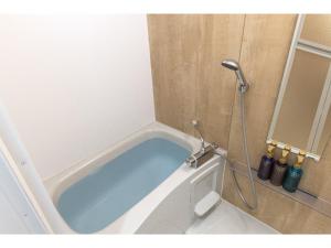 a bath tub with a shower in a bathroom at エンズ　マリーナ　イン　マシキ　コンド・ホテルズ in Ginowan