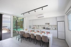 a white kitchen and dining room with a table and chairs at Kube Luxury Villas in Ayia Napa