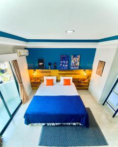 um quarto com uma cama grande com paredes azuis e almofadas laranja em BH Baan Paradise Hotel em Patong Beach