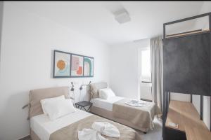 a white bedroom with two beds and a table at Kube Luxury Villas in Ayia Napa