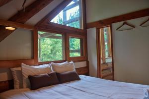 a bedroom with a white bed with three windows at SUNNSNOW Loghouse in Otari